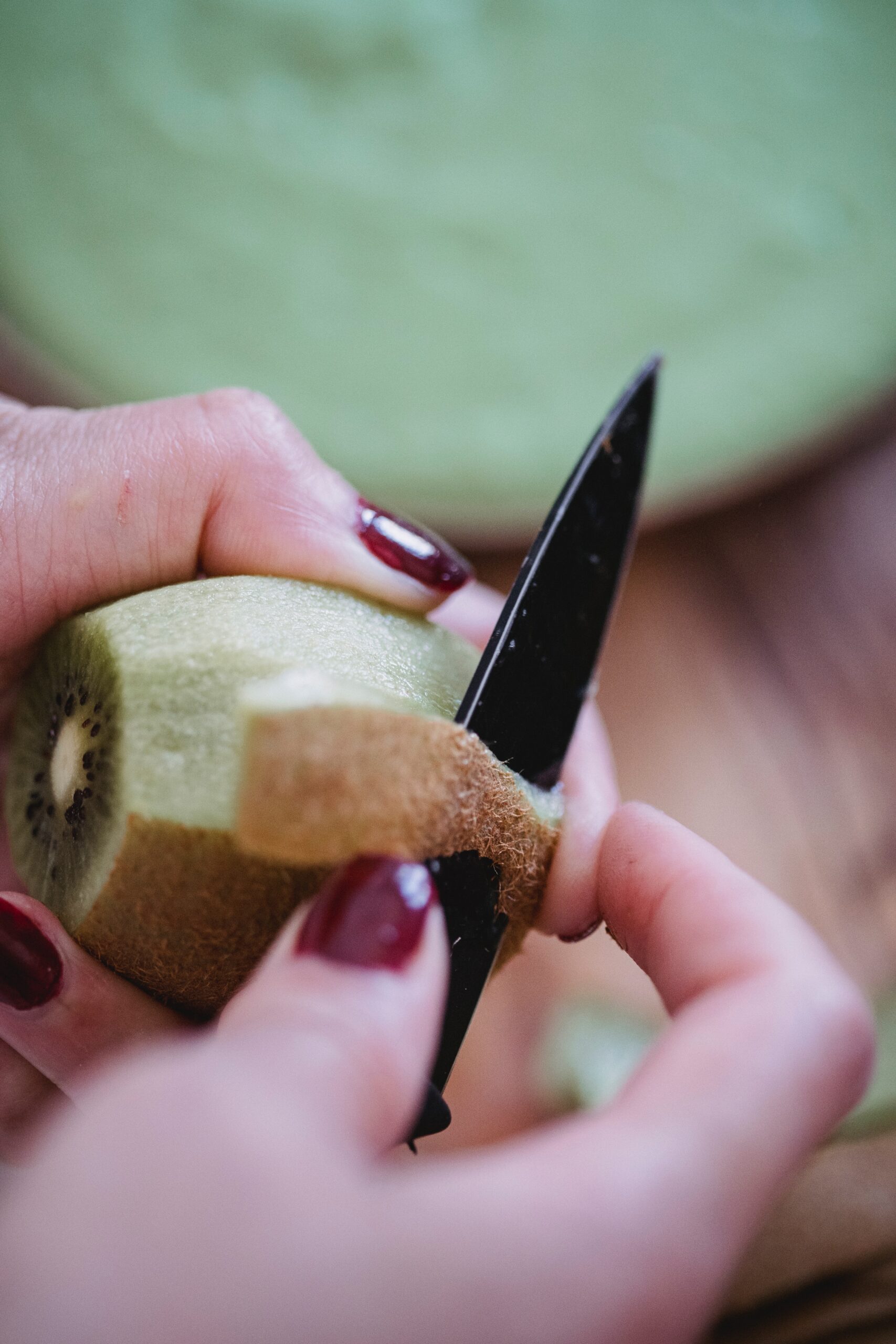 Hands peeling a kiwi to reveal the layers beneath its skin